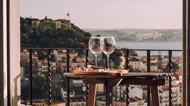 Dos copas de vino junto a un aperitivo en la terraza de una habitación de hotel con fantásticas vistas al mar.
