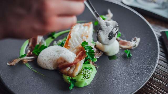 Primer plano de un plato de pescado de alta cocina, artísticamente presentado sobre una vajilla de diseño.