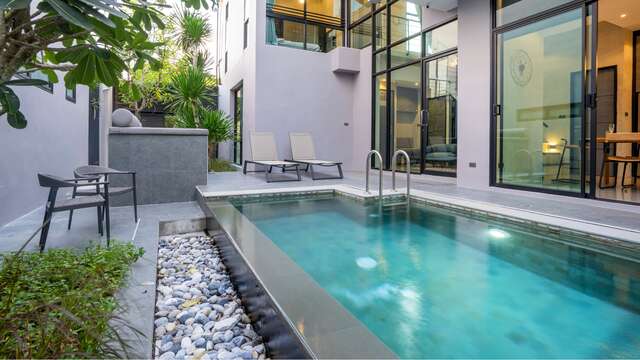 Moderna piscina de diseño situada junto a la fachada acristalada de un hotel exclusivo.
