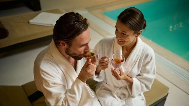 Pareja en albornoz descansando en una hamaca mientras toman un té, disfrutando de su regalo de escapada relax.