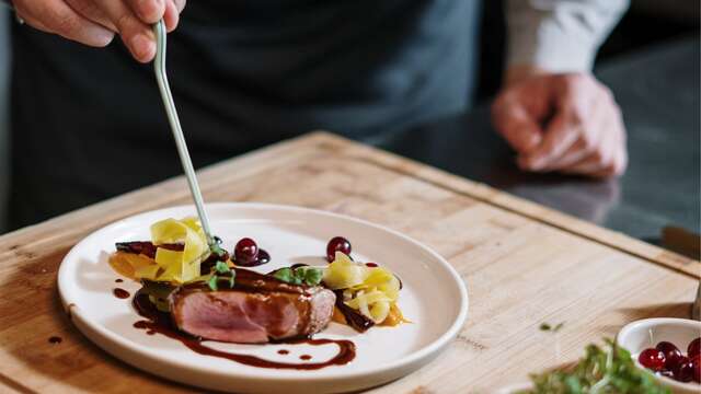 Chef professionnel préparant un plat gourmet dans la cuisine d'un hôtel.