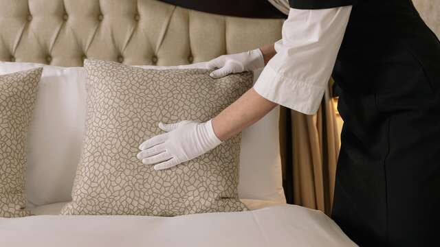 Le personnel d'un hôtel de luxe préparant avec soin le lit double d'une suite impeccable.