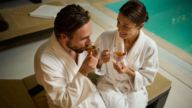 Couple en peignoir buvant du thé dans l'espace détente, la touche finale parfaite à un cadeau de nuit romantique avec spa.