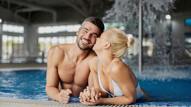 Een pasgetrouwd stel kust elkaar in een spa, genietend van hun onvergetelijke huwelijkscadeau.