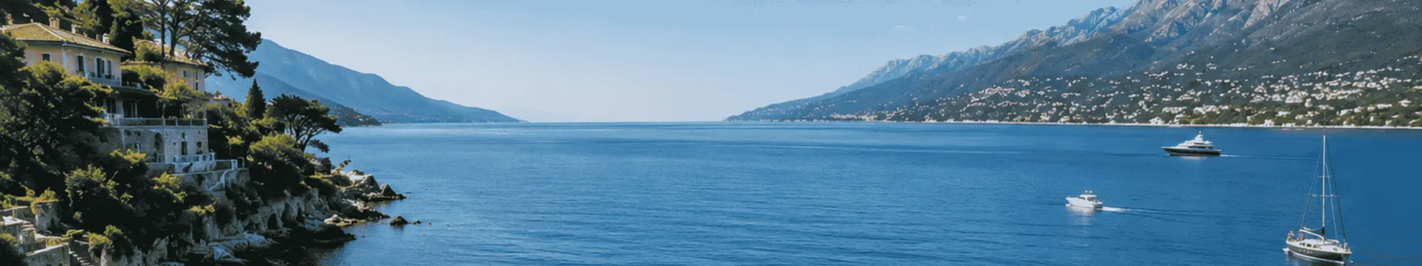 Lush green hills with buildings flank a serene blue lake with boats under a clear sky.
