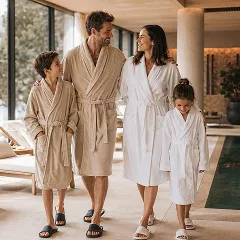 A family of four in bathrobes walking together through a bright, modern spa area.
